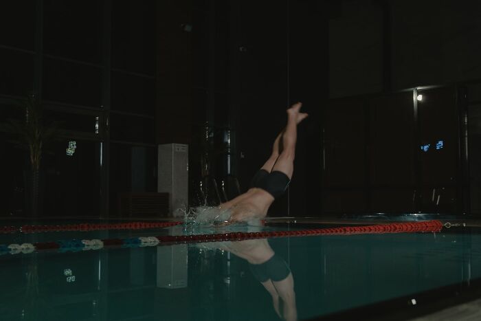 A person diving headfirst into a dark indoor pool illustrating survival tips that won't help you.