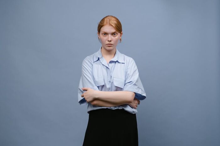 Young woman with crossed arms and serious expression representing entitled patients demanding special treatment.