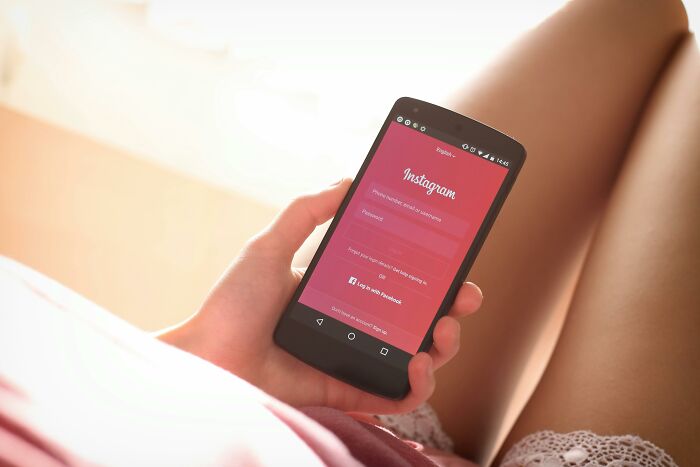 Person holding smartphone showing Instagram login screen, representing people share things that improved life online. - 11