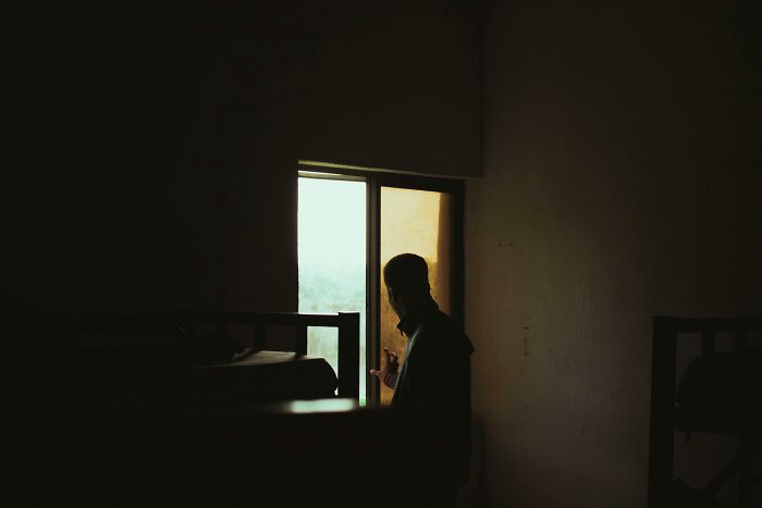 Silhouette of a person near a window in a dark room, evoking thoughts of neighbor tales and moving to the woods.