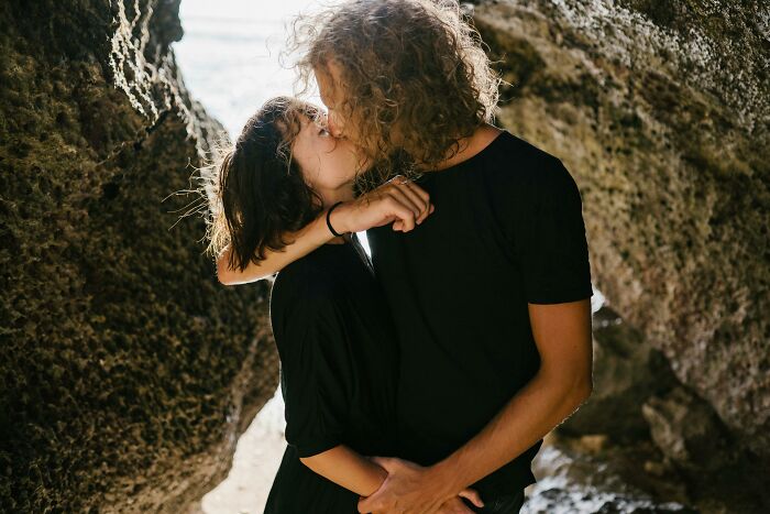 Couple kissing intimately near rocky cave entrance representing red flag behavior in romantic relationships. - 8