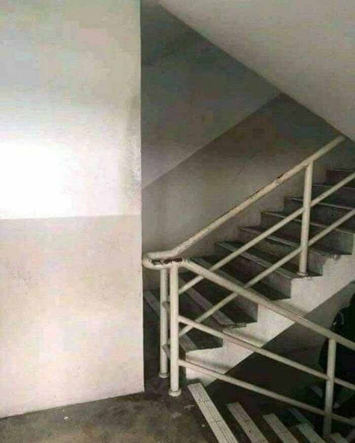 Staircase with a handrail improperly ending at a wall, illustrating engineering mistakes despite degrees and knowledge.