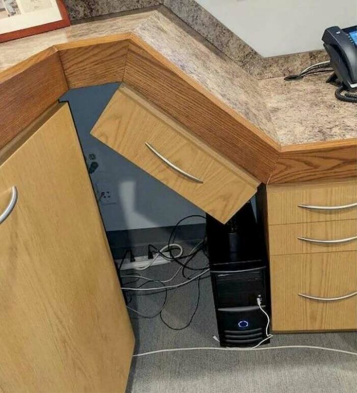 Office desk with misaligned drawer and computer tower underneath showcasing hilariously dumb engineering mistakes and design errors.