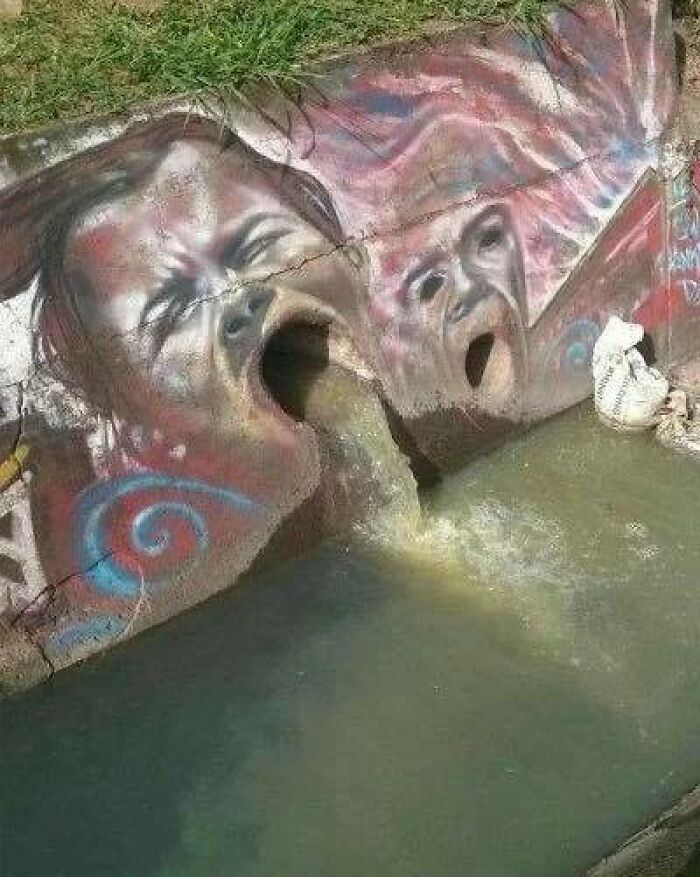 Graffiti art showing faces vomiting and spilling into a water canal, combining trash and culture in a chaotic scene.