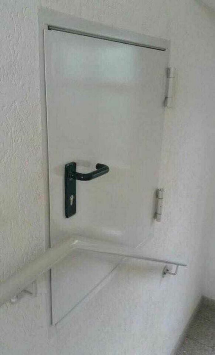 Small door with a handle and railing blocking it, showcasing hilariously dumb engineering mistakes and design flaws.