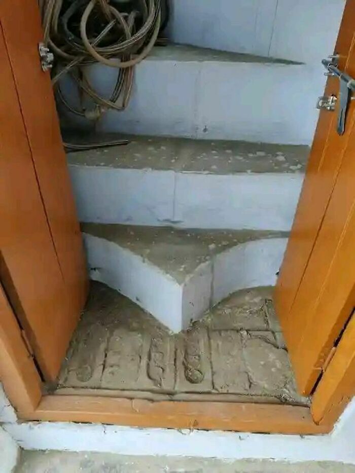 Narrow and uneven stairs with improper landing area inside a small wooden door, showcasing engineering mistakes.