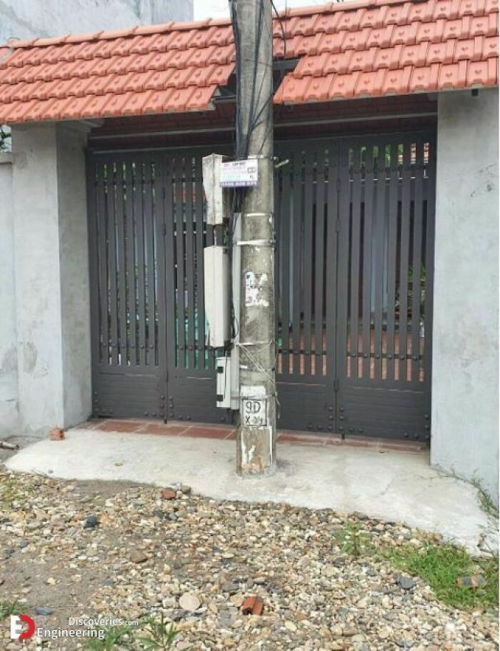 Utility pole placed directly in front of a gate, showcasing hilariously dumb engineering mistakes outdoors.