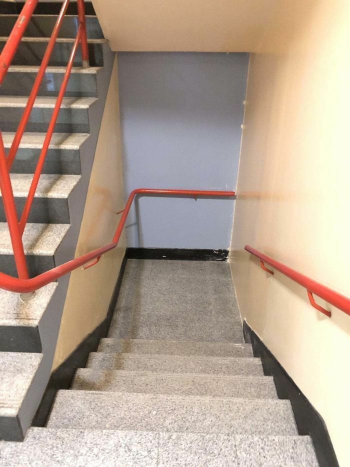 Staircase with red handrails leading directly into a wall, illustrating hilariously dumb engineering mistakes.
