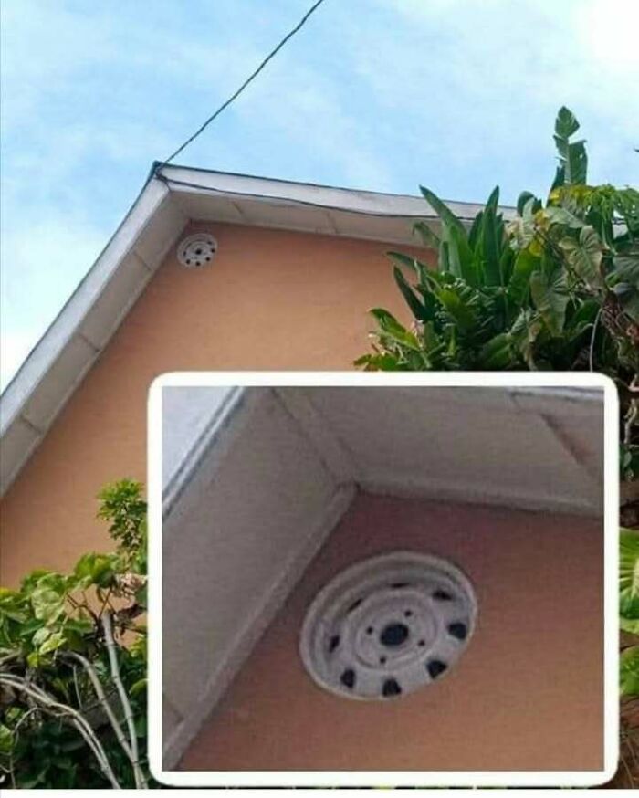 Car wheel rim mistakenly installed on the exterior wall of a house, highlighting engineering design mistakes.