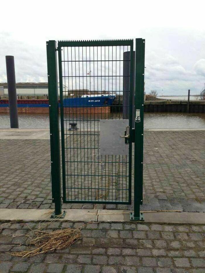 Green metal gate with a lock that leads to an empty space, illustrating hilariously dumb engineering mistakes.