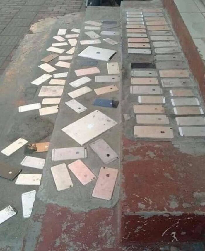 Old and broken iPhones and iPads arranged on the ground, combining trash and culture in a chaotic display.