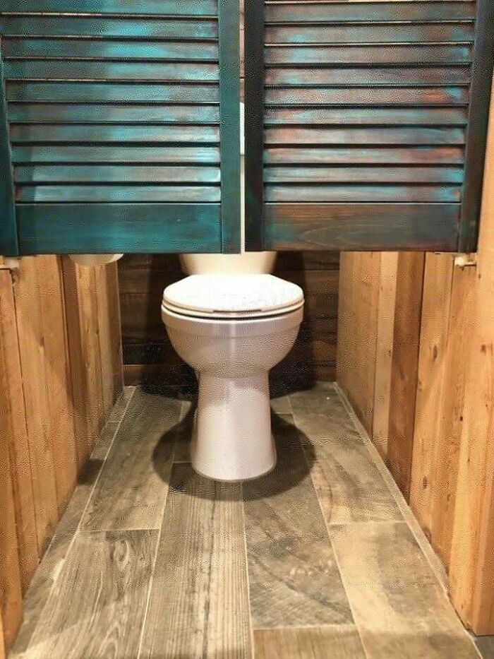 Toilet with swinging wooden doors that prevent proper privacy, an example of hilariously dumb engineering mistakes.