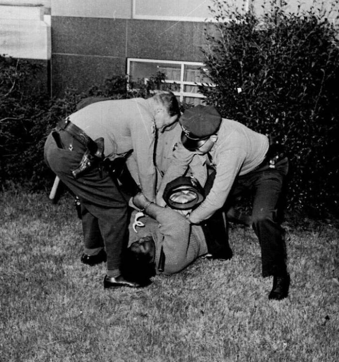Two police officers restraining a man on the ground in a unique old photo with a powerful historical story behind it