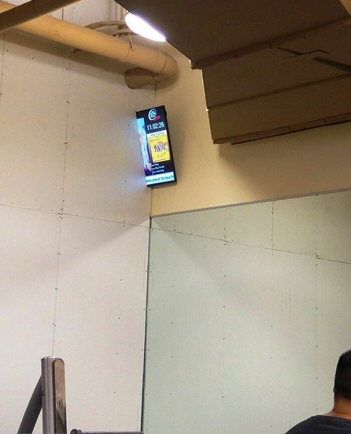 Digital clock screen mounted incorrectly high on a wall, showing a hilariously dumb engineering mistake.
