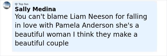 Pamela Anderson and Liam Neeson smiling together on the red carpet, sharing a close and affectionate moment.
