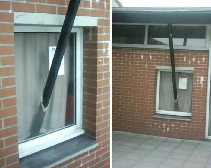 Pipe installed through a window on a brick building, illustrating a hilariously dumb engineering mistake.