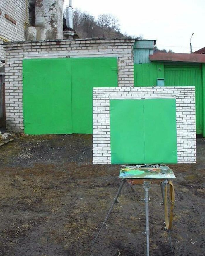 Green garage doors partially painted on canvas in a chaotic outdoor scene combining trash and culture humor.