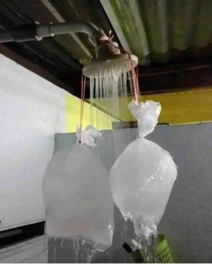 Showerhead with two plastic bags tied to it, a humorous engineering mistake causing water to flow unusually.