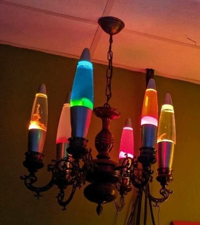 Vintage chandelier with colorful lava lamps instead of bulbs, combining trash and culture in a chaotic decor style.