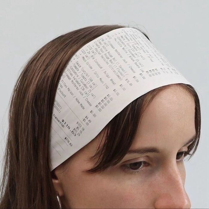 Person wearing a headband made from a printed receipt, showcasing chaotic trash and culture combined in a humorous way.