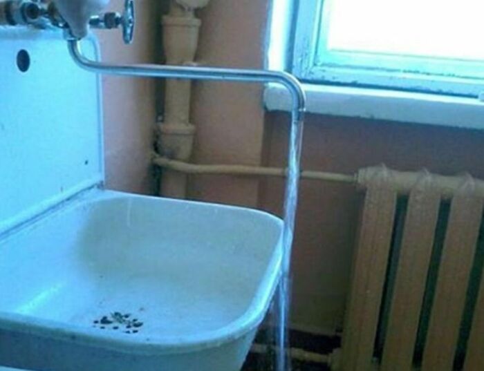 Plumbing engineering mistake showing water flowing outside the sink while the faucet is incorrectly installed.