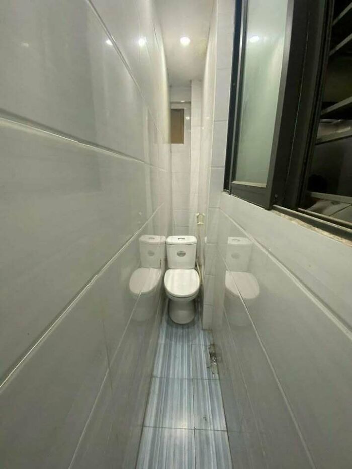 Narrow bathroom with a toilet placed in a cramped space showing hilariously dumb engineering mistakes.