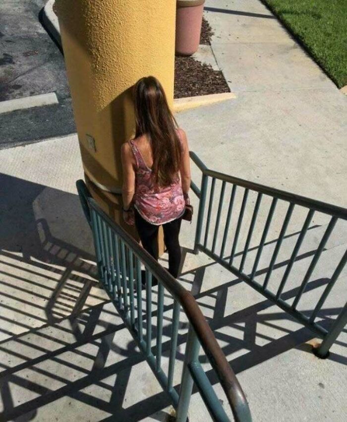 Woman facing a large pillar blocking the path, highlighting engineering mistakes in design and construction.