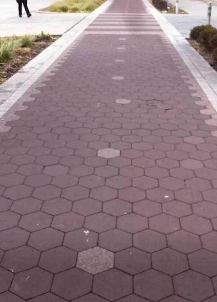 Sidewalk with hexagonal tiles featuring an engineering design mistake with mismatched tile shapes and colors.