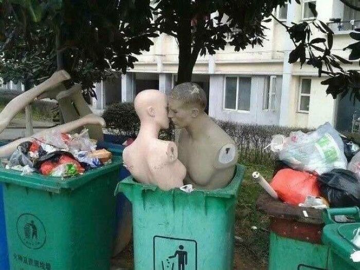 Two mannequin torsos placed in trash bins outdoors, blending trash and culture in a chaotic urban scene.