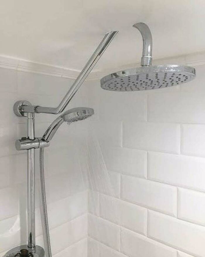 Shower setup with two showerheads pointing away from the shower space, showing an engineering mistake in plumbing installation.