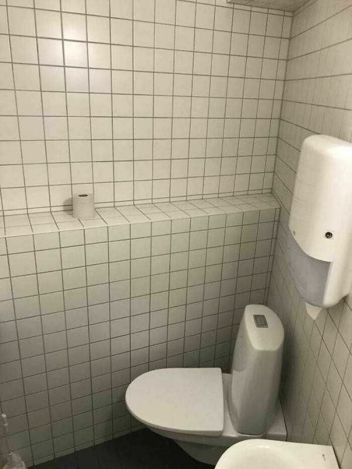 Bathroom with tiled shelf above toilet holding a single toilet paper roll, showcasing engineering degree mistakes.