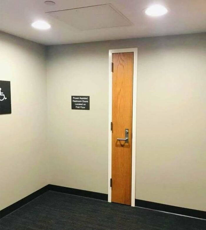 Narrow wooden door with a handle in a hallway, showcasing a hilariously dumb engineering mistake in design.