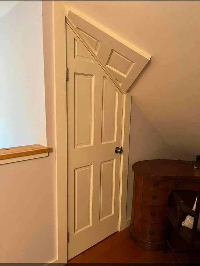 Door with a triangular top cutout fitting oddly under a slanted ceiling showing funny engineering mistakes.