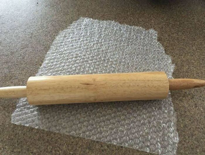 Wooden rolling pin placed on bubble wrap, showcasing a chaotic combination of trash and culture humor.