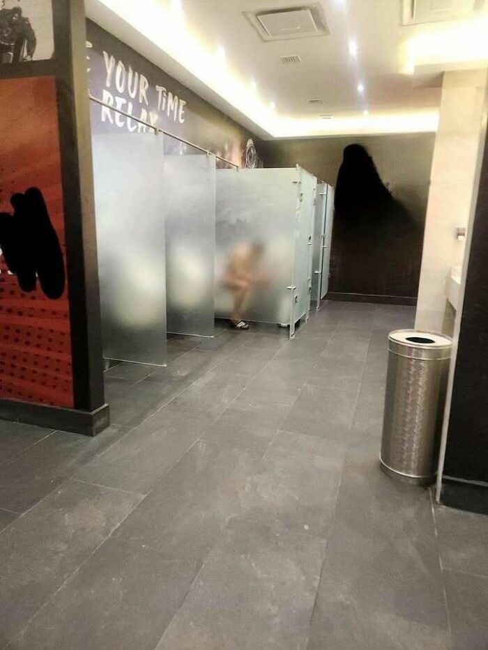 Bathroom stalls with frosted glass doors showing a person sitting inside, illustrating hilariously dumb engineering mistakes.