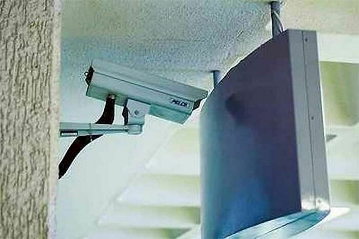 Security camera mounted directly behind a large TV screen, illustrating engineering mistakes despite degrees.