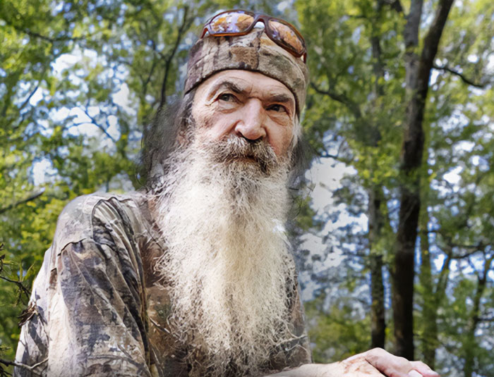 Older man with long white beard in camouflage clothing and hat outdoors, representing stars we've lost this year.