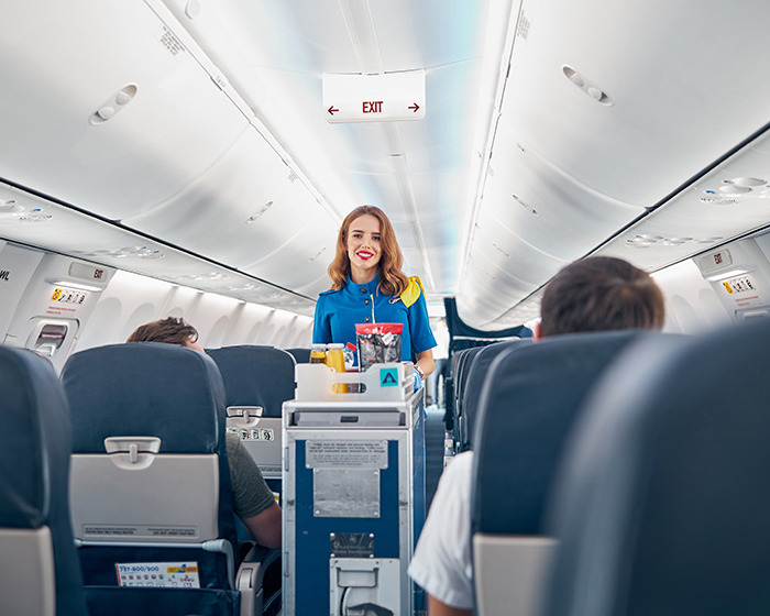 Flight attendant serving passengers inside the airplane, related to passenger allergy request announcement debate. Flight attendant serving passengers inside the airplane, related to passenger allergy request announcement debate.