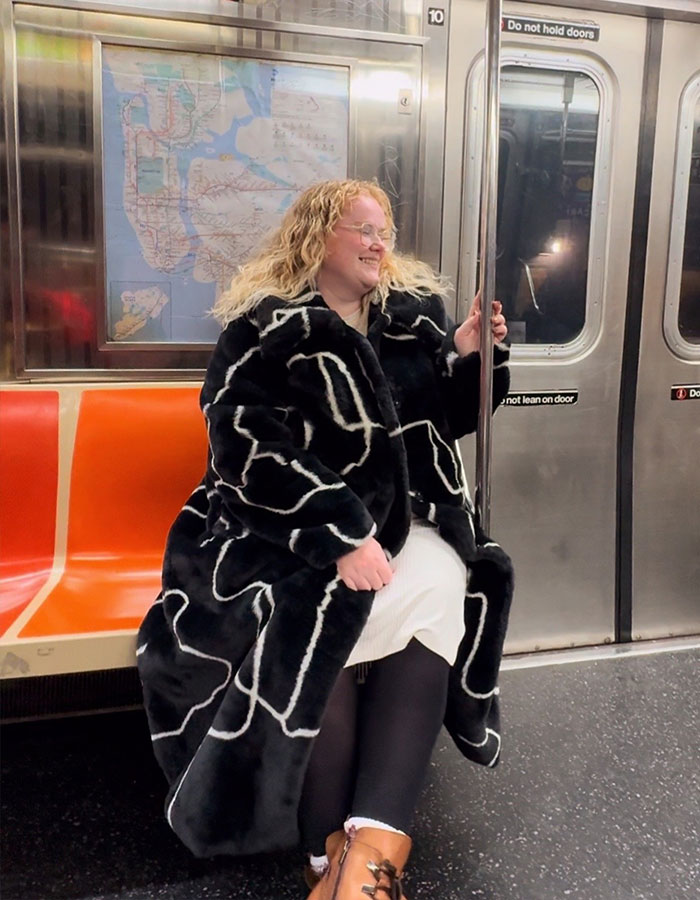 Plus-size traveler sitting on subway seat, smiling and holding a pole, highlighting issues with booking multiple airline seats.