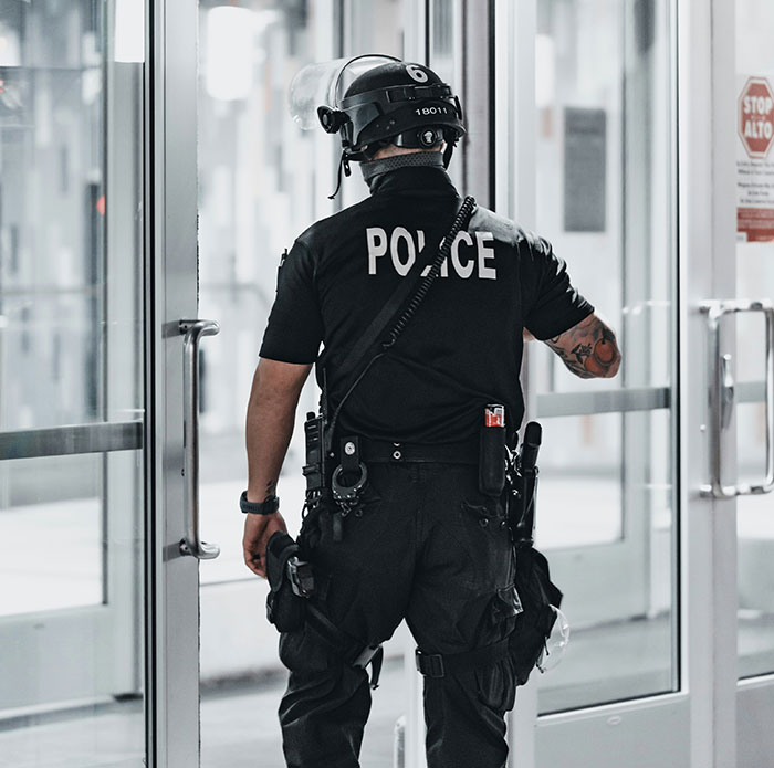 Police officer in tactical gear seen from behind, responding to incident involving man threatening to explode plane mid-flight.