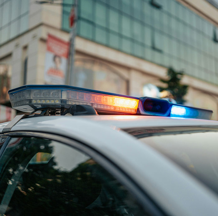 Police car with flashing lights parked near a building, related to man threatening to explode plane mid-flight incident.