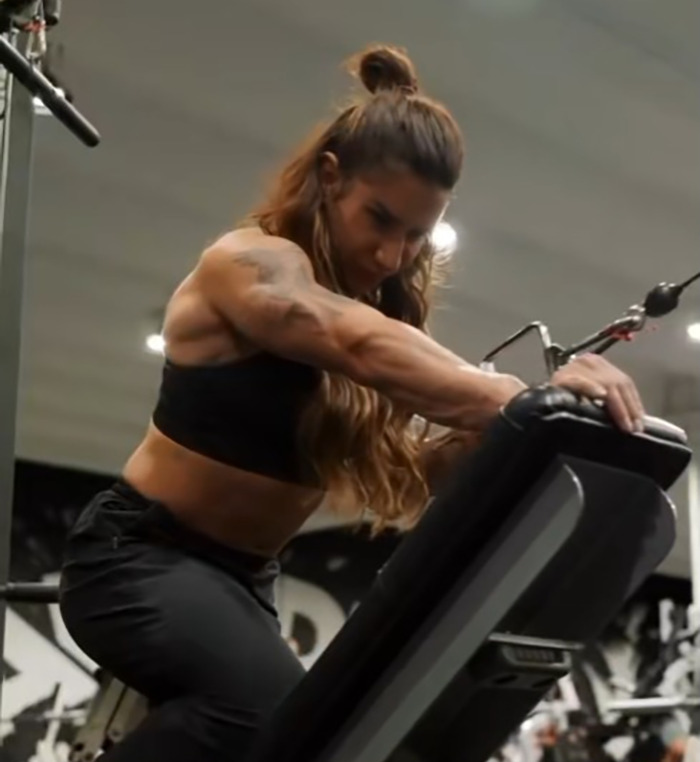 Powerlifter Stefi Cohen training intensely in gym, showcasing muscular arms and focused expression during workout session.