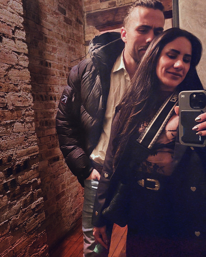 Powerlifter Stefi Cohen taking a mirror selfie with a man in a brick-walled room, sparking steroid rumors.
