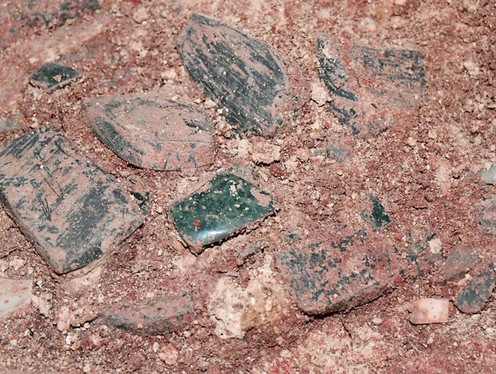 Unearthed Maya royal tomb artifacts partially covered in dirt at an archaeological excavation site in Texas. - 11
