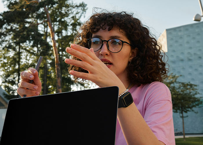 Woman with glasses using laptop outdoors, demonstrating discoveries made by private investigators during their job. - 15