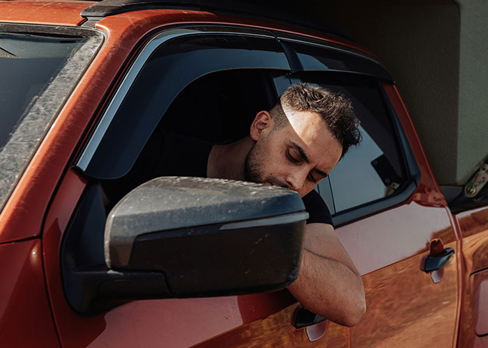 Private investigator leaning out of a red car window, conducting surveillance during an investigation for strange discoveries. - 35