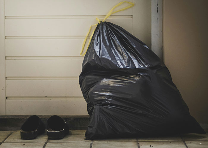 Black garbage bag tied with yellow string next to a pair of shoes on a tiled floor, showing strange things private investigators discovered. - 30