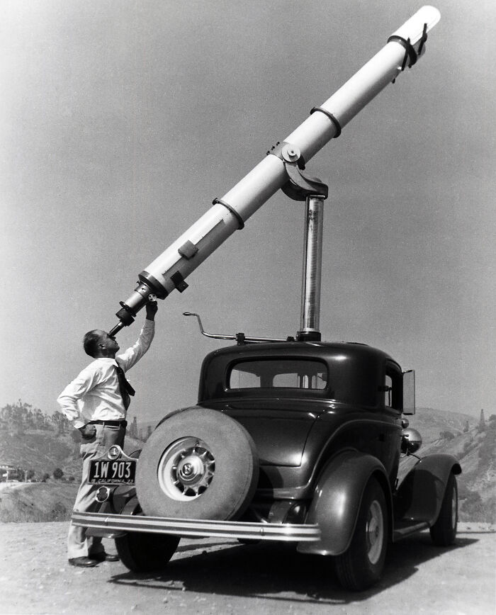 Man using a large telescope mounted on a vintage car in a unique old photo with an incredible story behind it