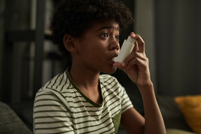 Young boy using an inhaler at home, highlighting the impact of parents punishing their kids way too far.