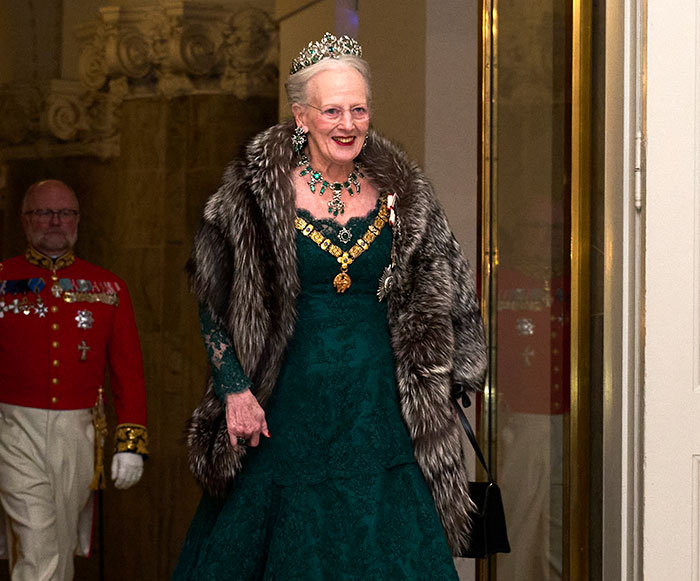 Royal woman wearing a tiara and fur stole, attending a formal event, representing royals who walked away from power.